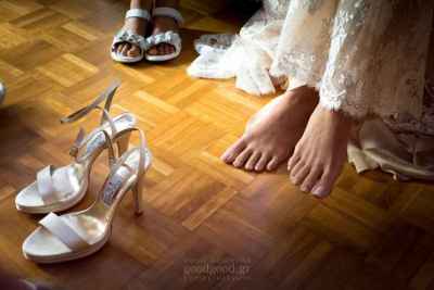 φωτογραφία στην οποία φαίνονται τα παπούτσια της νύφης και τα πόδια της λίγο πριν τα φορέσει
