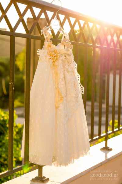 Λευκό φόρεμα βάπτισης κρεμασμένο σε κάγγελα λουσμένο με ήλιο