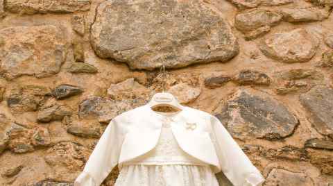 Christening gown hanging on a stone wall